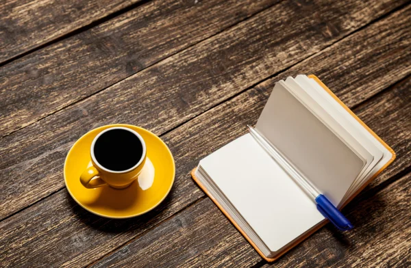 Xícara de café e caderno em uma mesa . — Fotografia de Stock