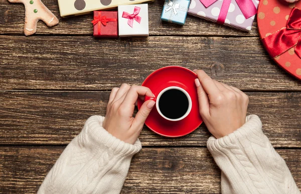 Kadın holding fincan kahve Noel hediyesi yakınındaki ahşap tablo — Stok fotoğraf