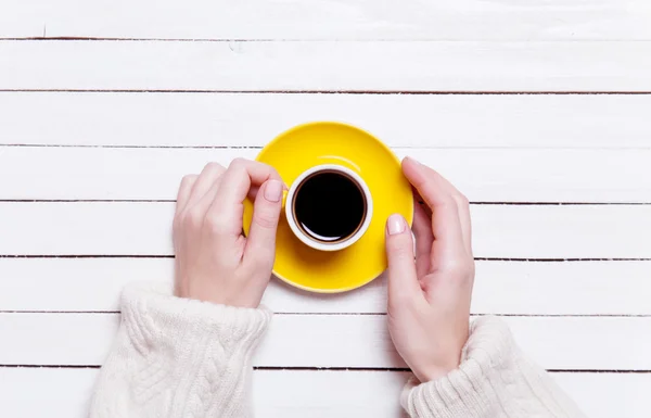 Kvinnliga händer som håller kopp kaffe på träbord. — Stockfoto