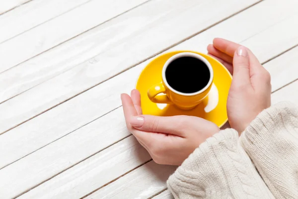 Mains féminines tenant une tasse de café sur une table en bois . — Photo