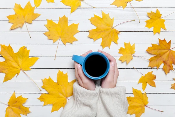 Vrouwelijke handen met kopje koffie op houten tafel. — Stockfoto