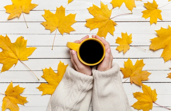 Kvinnliga händer som håller kopp kaffe på träbord. — Stockfoto