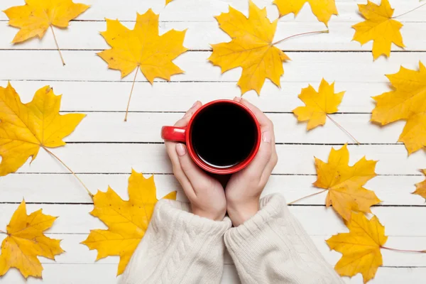 Kvinnliga händer som håller kopp kaffe på träbord. — Stockfoto