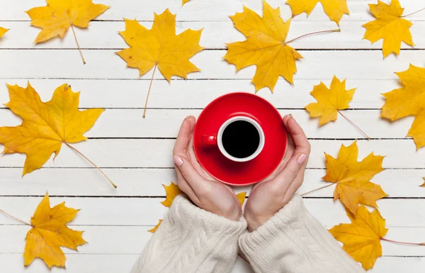 Vrouwelijke handen met kopje koffie op houten tafel. — Stockfoto