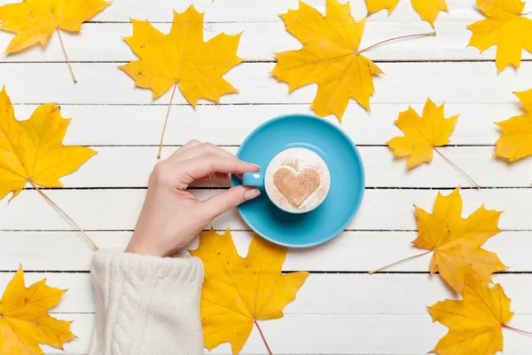 Mani femminili che tengono la tazza di caffè sul tavolo di legno . — Foto Stock