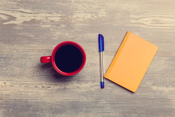 Xícara de café e caderno em uma mesa . — Fotografia de Stock