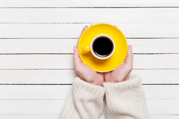 Frauenhände halten Tasse Kaffee auf Holztisch. — Stockfoto