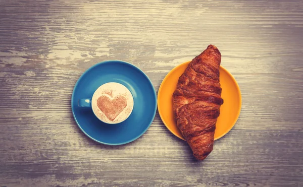 Croissant français et tasse de café sur une table en bois — Photo