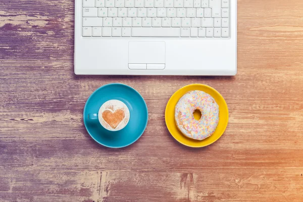 Cup of coffee and donut with notebook on a table. — Stock Photo, Image