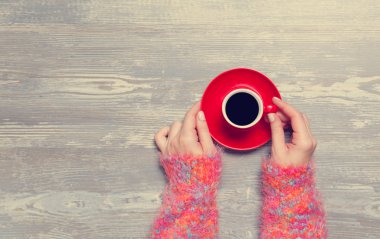 Kadın elleri bir fincan kahve tutuyor..