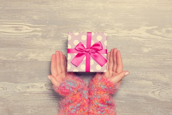 Female hands holding gift on wooden table. — Stock Photo, Image