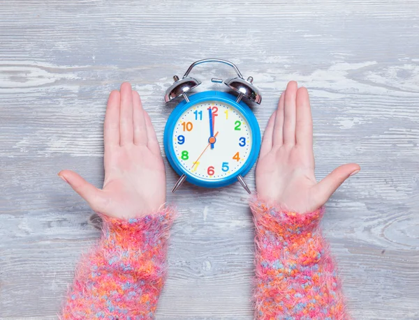 Female hands holding clock on a table. — Stock Photo, Image