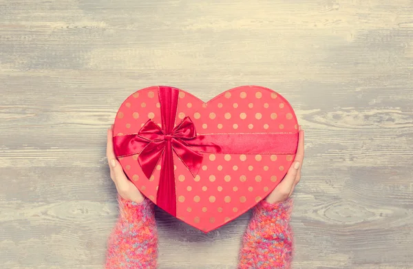 Female hands holding gift on wooden table. — Stock Photo, Image