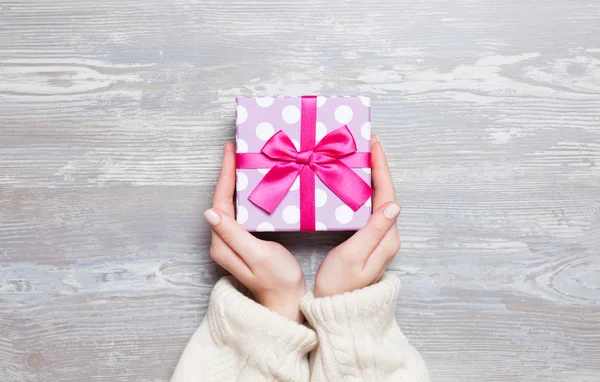 Mani femminili che tengono il regalo sul tavolo di legno. — Foto Stock