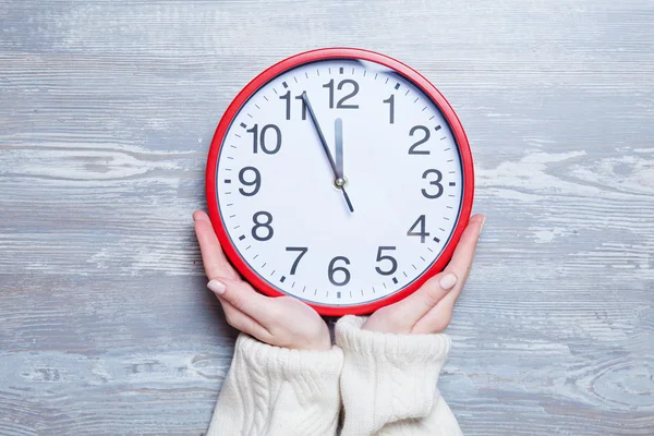 Manos femeninas sosteniendo el reloj en una mesa . — Foto de Stock