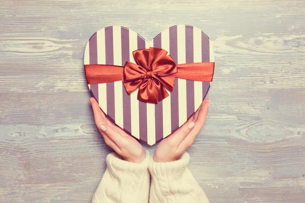 Female hands holding gift on wooden table. — Stock Photo, Image