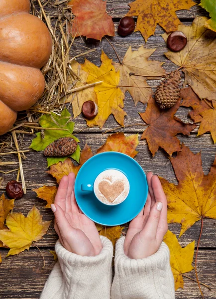 Vrouwelijke holding kopje koffie op herfst achtergrond. — Stockfoto