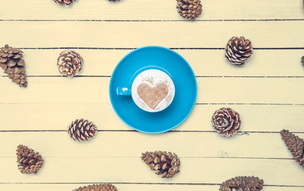 Taza de café y cono de pino sobre una mesa blanca . — Foto de Stock