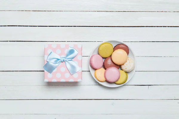 Macaron e regalo su tavola bianca . — Foto Stock