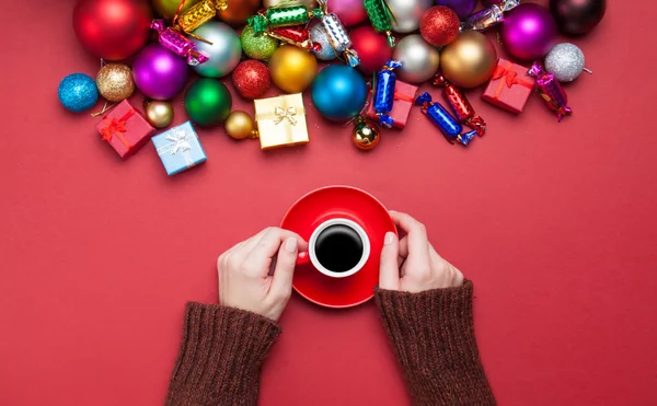 Ragazza che tiene una tazza di caffè vicino ai giocattoli di Natale . — Foto Stock