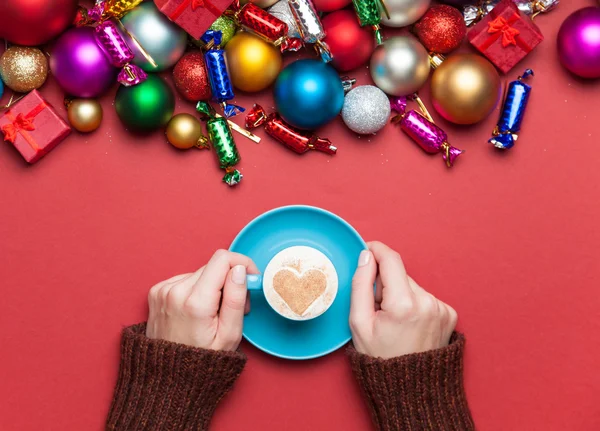 Girl holding cup of coffee near christmas toys. — Stock Photo, Image