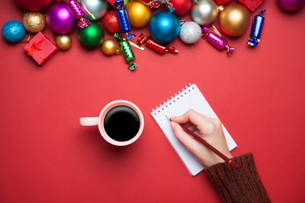 Hand schrijven iets in in het notitieblok in de buurt van Kerstmis speelgoed. — Stockfoto