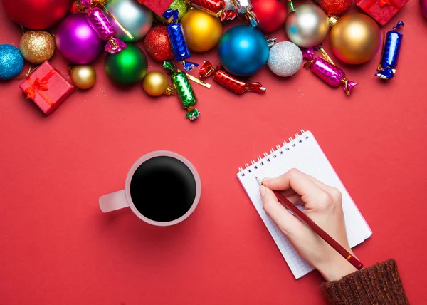 Scrivere qualcosa nel quaderno vicino ai giocattoli natalizi . — Foto Stock