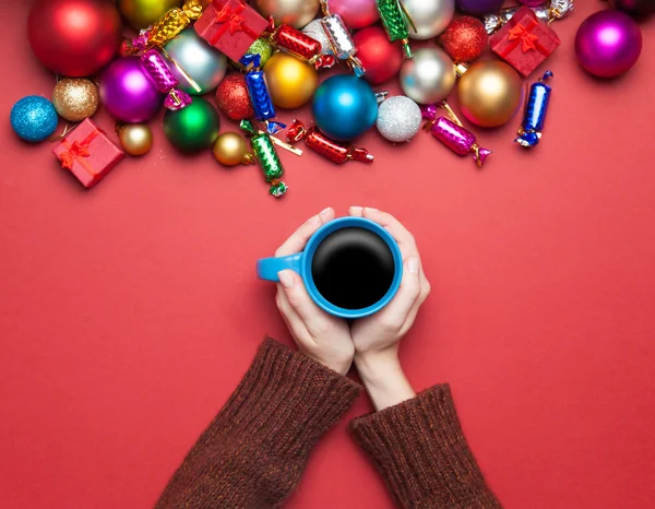 Дівчина тримає чашку кави біля різдвяних іграшок . — стокове фото