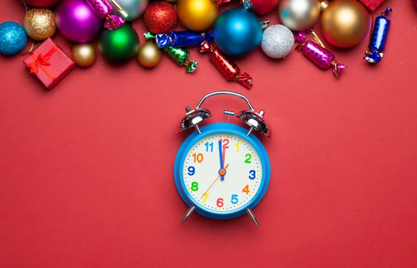 Relógio despertador e brinquedos de Natal na mesa vermelha . — Fotografia de Stock