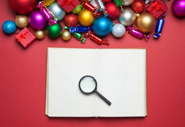 Loupe and book near christmas toys. — Stock Photo, Image