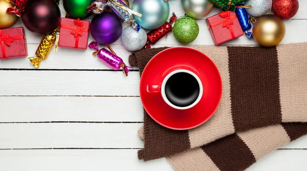 Red cup of coffee and scarf with christmas toys. — Stock Photo, Image