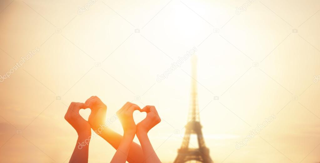 Two lovers showing heart shapes with hands and parisian Eiffel t