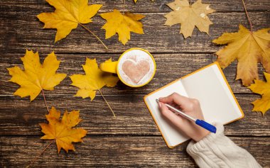 Bir şey kahve yakınındaki Not defterinizdeki yazma el.