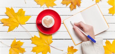 Bir şey kahve yakınındaki Not defterinizdeki yazma el.