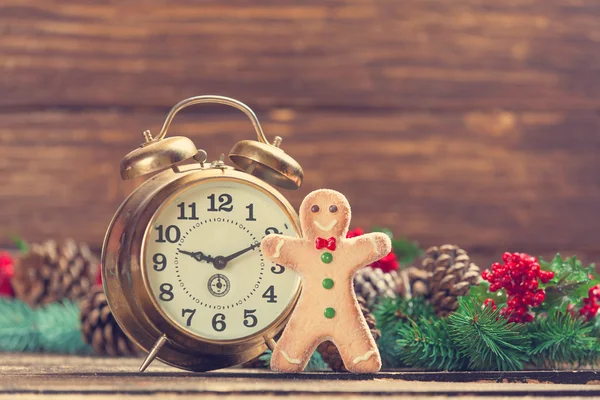 Alarm clock near Pine branches and gingerbread on wooden table. — Stock Photo, Image