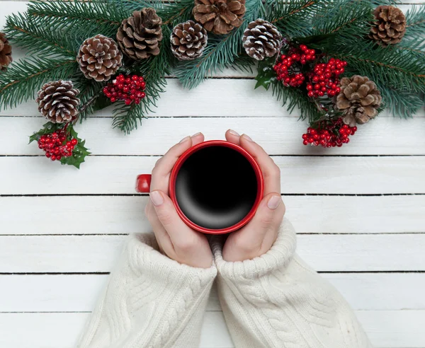 Flicka håller kopp kaffe nära Pine grenar — Stockfoto