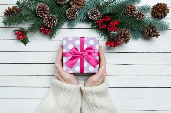Vrouwelijke handen met geschenk doos en pine takken. — Stockfoto