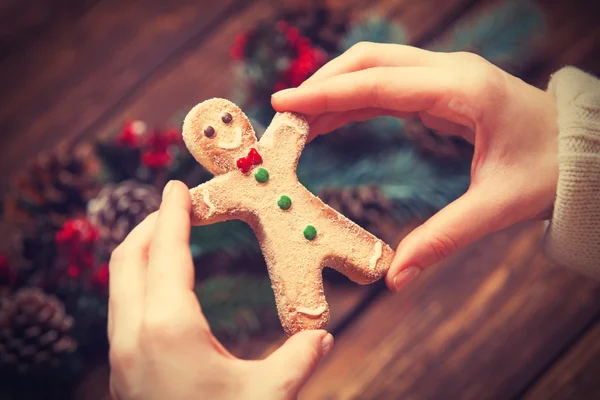 Female holding gingerbread man near pine branches. — Stock Photo, Image