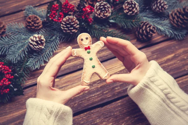 Female holding gingerbread man near pine branches. — Stock Photo, Image