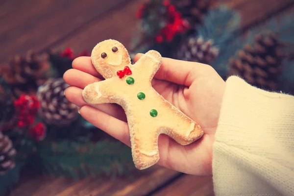 Female holding gingerbread man near pine branches. — Stock Photo, Image