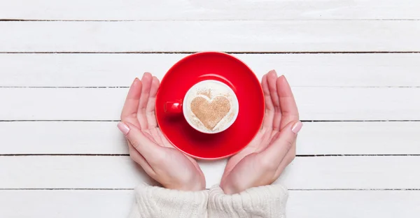 Female hands holding cup of coffee on wooden table. — Stock Photo, Image