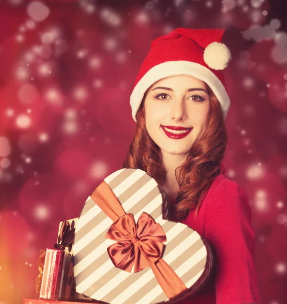 Pelirroja chica con regalos sobre fondo rojo —  Fotos de Stock