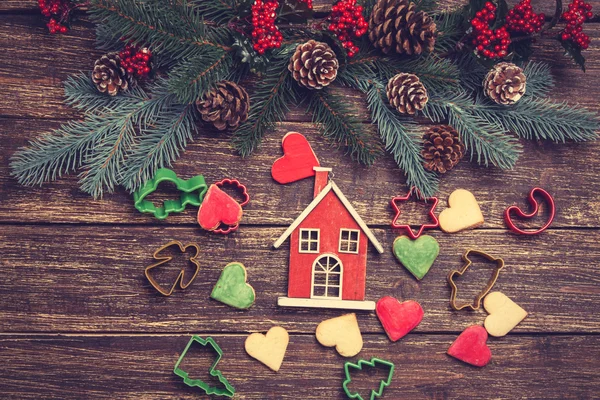 Lebkuchen und selbst gebackenes Spielzeug in der Nähe von Kiefernzweigen auf einer Holzlasche — Stockfoto