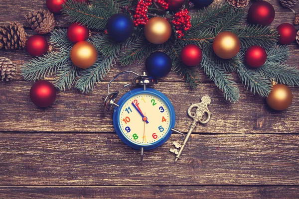 Alarm clock and vintage key near Pine branches on wooden table. — Stock Photo, Image