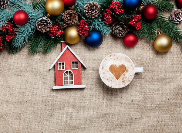 Hot cappuccino with christmas tree shape and toy home on a table — Stock Photo, Image