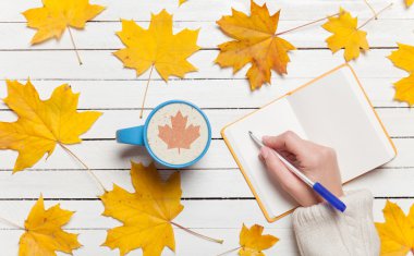 Bir şey kahve yakınındaki Not defterinizdeki yazma el.