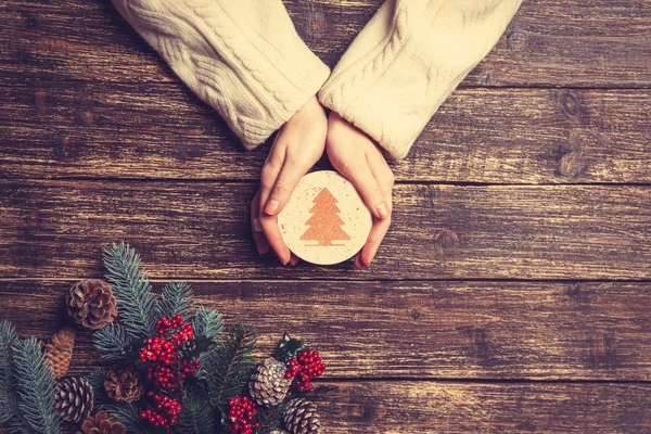 Vrouwelijke bedrijf kopje koffie met crème kerstboom op een tabl — Stockfoto