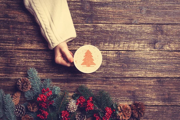 Kvinnliga anläggning kopp kaffe med grädde julgran på en tabl — Stockfoto