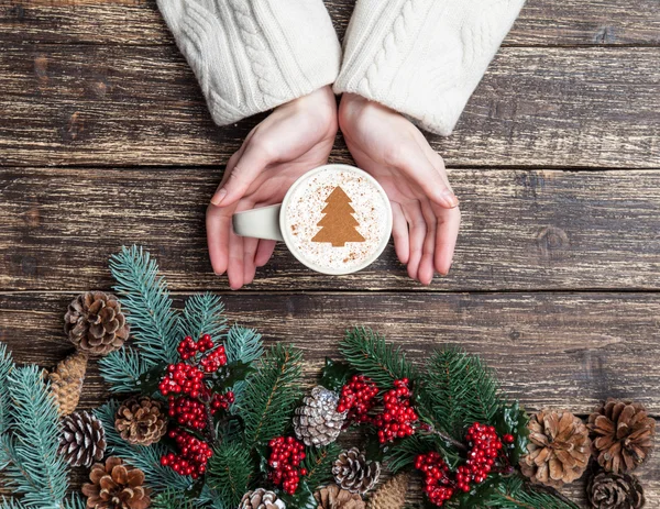 Ženské hospodářství šálek kávy s krémem vánoční strom na tabl — Stock fotografie