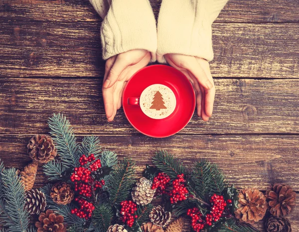 Femme tenant tasse de café avec arbre de Noël crème sur une table — Photo